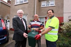 (l-r) Ali Thomas, leader of Neath Port Talbot council, householder Gerald Flynn and waste operative Alan Freeman with one of the new kerbside food waste caddies which uses the BagFlag system