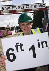 Cllr Neil Swannick with a sign displaying the new height for the bars
